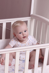 Little boy sitting in a crib