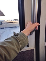 Hand holding handle inside monorail train ride between airport terminals