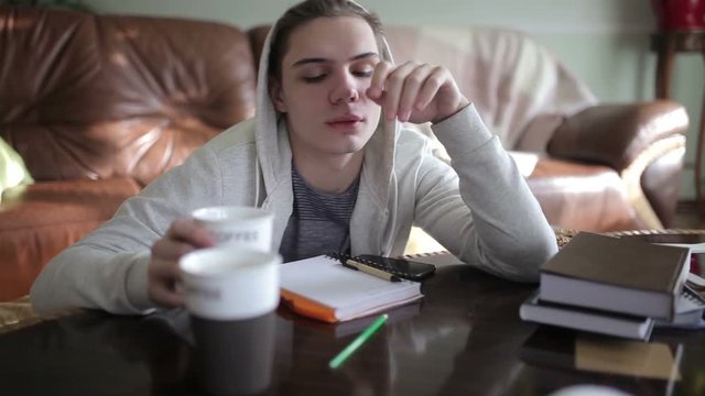 Sleepy male student drinks coffee.