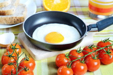 Fried egg, toast bread, fresh juice, tomatoes and oranges