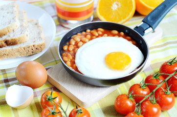 Fried egg with beans, toast bread, fresh juice, tomatoes and oranges