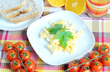 Scrambled eggs, toast bread, fresh juice, tomatoes and oranges