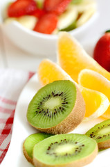 Naklejka na ściany i meble Bowl with fruit salad - pieces of orange, banana, strawberry and kiwi