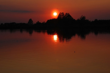 Obraz premium Sunset behind the trees on the lake