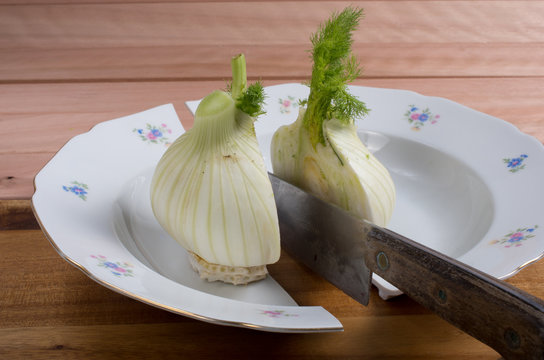 Drastic cut of a fennel on the wooden cutting board.