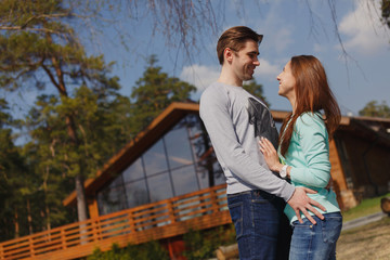 Cheerful couple standing in front of new house
