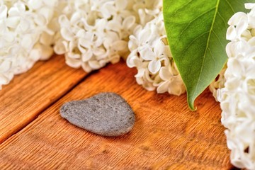 Heart shaped grey stone next to lilac blooms