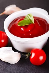 Tomato in front of bowl with ketchup