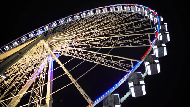 Huge observation wheel stops moving at night amusement park, entertainment