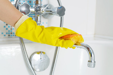 A woman cleaning bath at home. Female washing bathtub and faucet