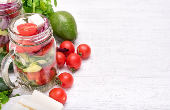 Homemade tomato salad with cucumber and feta in glass jar. Vegetarian concept. Background.