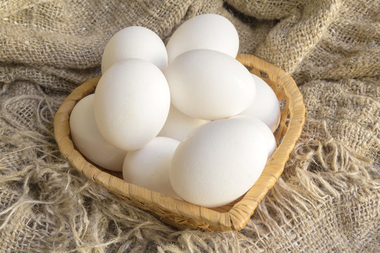 white eggs in a straw plate against the background of the canvas