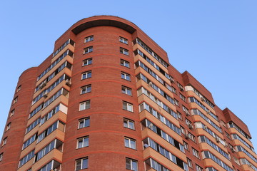 Fototapeta premium beautiful building for a multitude happy familiesIt stands tall building of orange brick for human habitation. blue sky