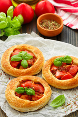 Homemade pie of puff pastry with tomatoes, Basil and spices. Mini round tomato tart. Rustic style
