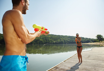 Paar am See bespritzt sich mit Wasserpistole