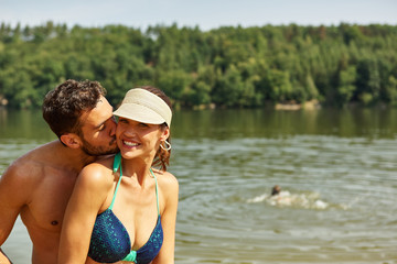 Glücklicher Mann küsst Frau am See