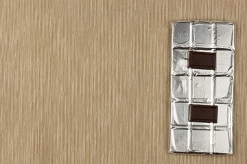 Chocolate wrapped in aluminum foil on bright tablecloth. Advertising on chocolate. Sales chocolate...
