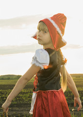little girl dressed as Little Red Riding Hood in the spring forest