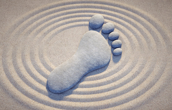 Fuß-Symbol aus Steinen im Sand