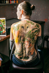 the process of creating a tattoo on the back of a girl