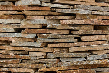 Stone flagstone lies a stack of the finished products masonry masonry wall background