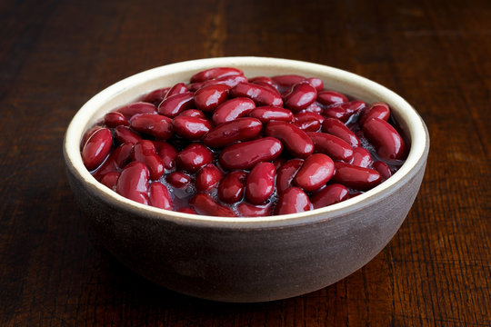 Red kidney beans in a dish in perspective. Isolated on dark wood