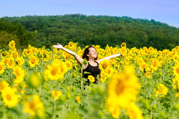 Fototapeta premium Girl stands in the field with sunflowers.