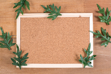 The cork board on the plank wood with the fake leaf