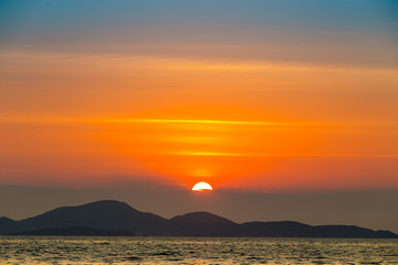 Sea landscape with sunset behind mountain and sea