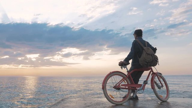 Girl on vintage bike enjoying beautiful sunrise on sea front