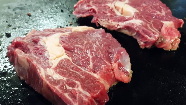 Frying Black angus entrecote steaks, on a frying pan, in a restaurant kitchen
