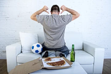 Tuinposter man celebrating goal at home couch watching football game on television © Wordley Calvo Stock