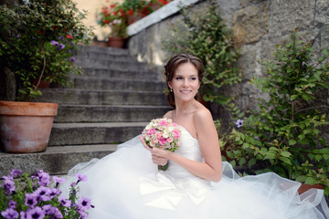 Beauty bride in bridal gown with bouquet on the nature. Beautiful model girl in a white wedding dress. Female portrait in the park. Woman with hairstyle. Cute lady outdoors