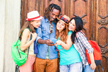 Group of multiracial friends looking mobile phone are traveling around the world - Mixed race students having fun using new smartphone technology - Concept of friendship and happiness  