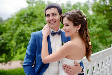 Wedding couple on the nature is hugging each other. Beautiful model girl in white dress. Man in suit. Beauty bride with groom. Female and male portrait. Woman with lace veil. Lady and guy outdoors