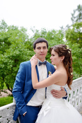 Fototapeta premium Wedding couple on the nature is hugging each other. Beautiful model girl in white dress. Man in suit. Beauty bride with groom. Female and male portrait. Woman with lace veil. Lady and guy outdoors