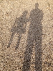 ombra di un papà che spinge la figlia sull'altalena