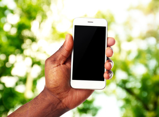 Hand shows mobile smart phone, nature blurred background