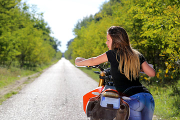 Fototapeta na wymiar young woman moving the motorbike on the road