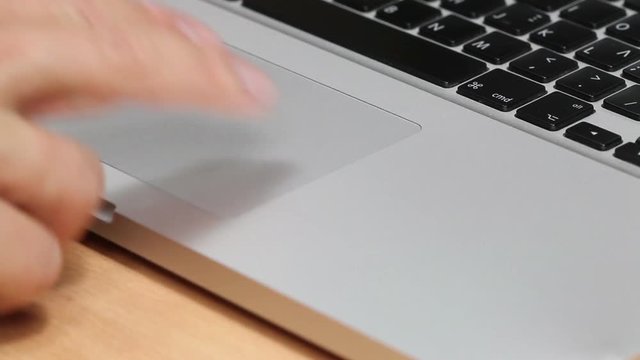 Man using a macbook laptop keyboard touchpad - gestures in this clip are double tap, pinch zoom and swipe, closeup shot.