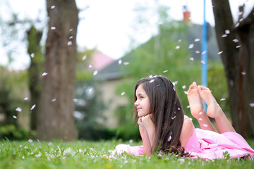 Little girl on green grass with petals