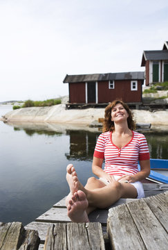 A woman sitting on a jetty in the archipelago of Stockholm, Sweden.