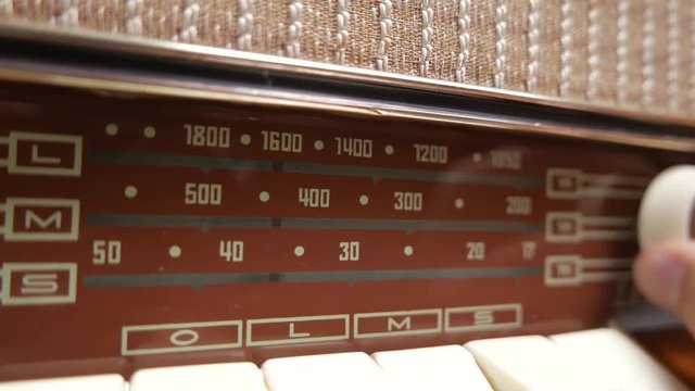 Old vintage radio being tuned by turning a dial. Male hand