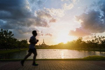Fototapeta premium Silhouette of man jogging In the park in twilight. Motion blur.
