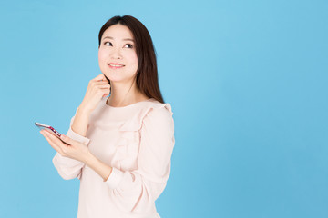 portrait of asian woman using smart phone isolated on blue background