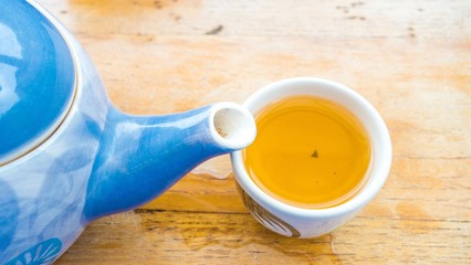 top view of tea pot and a cup of tea with wood background