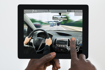 Person Playing Car Game On His Digital Tablet