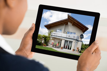 Person Looking At House On Digital Tablet