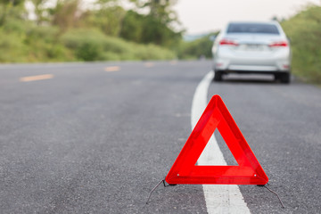 Red emergency stop sign and broken car on the road