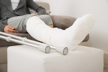 Woman With Plastered Leg Sitting On Couch